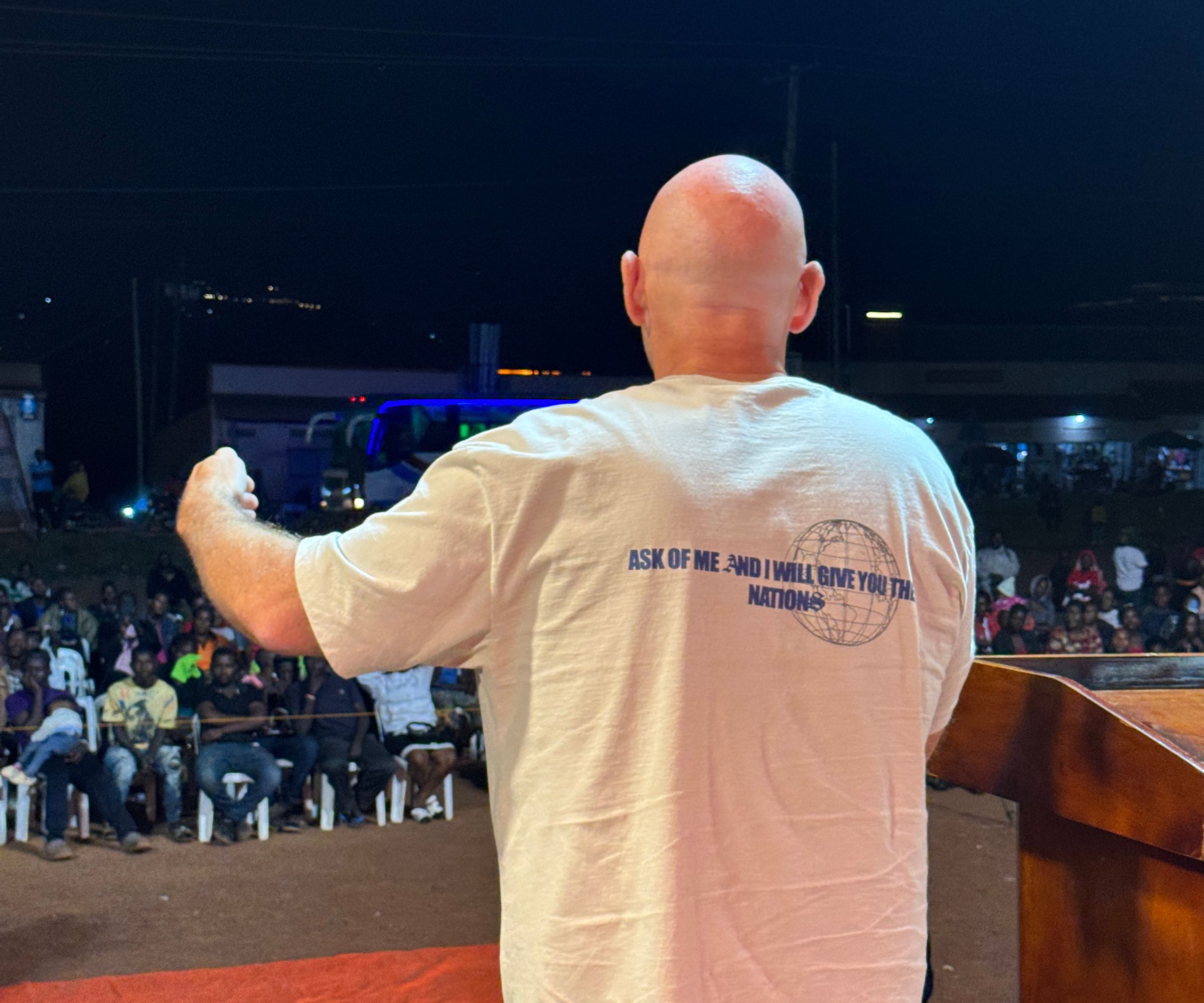 Man addressing crowd at outdoor nighttime event