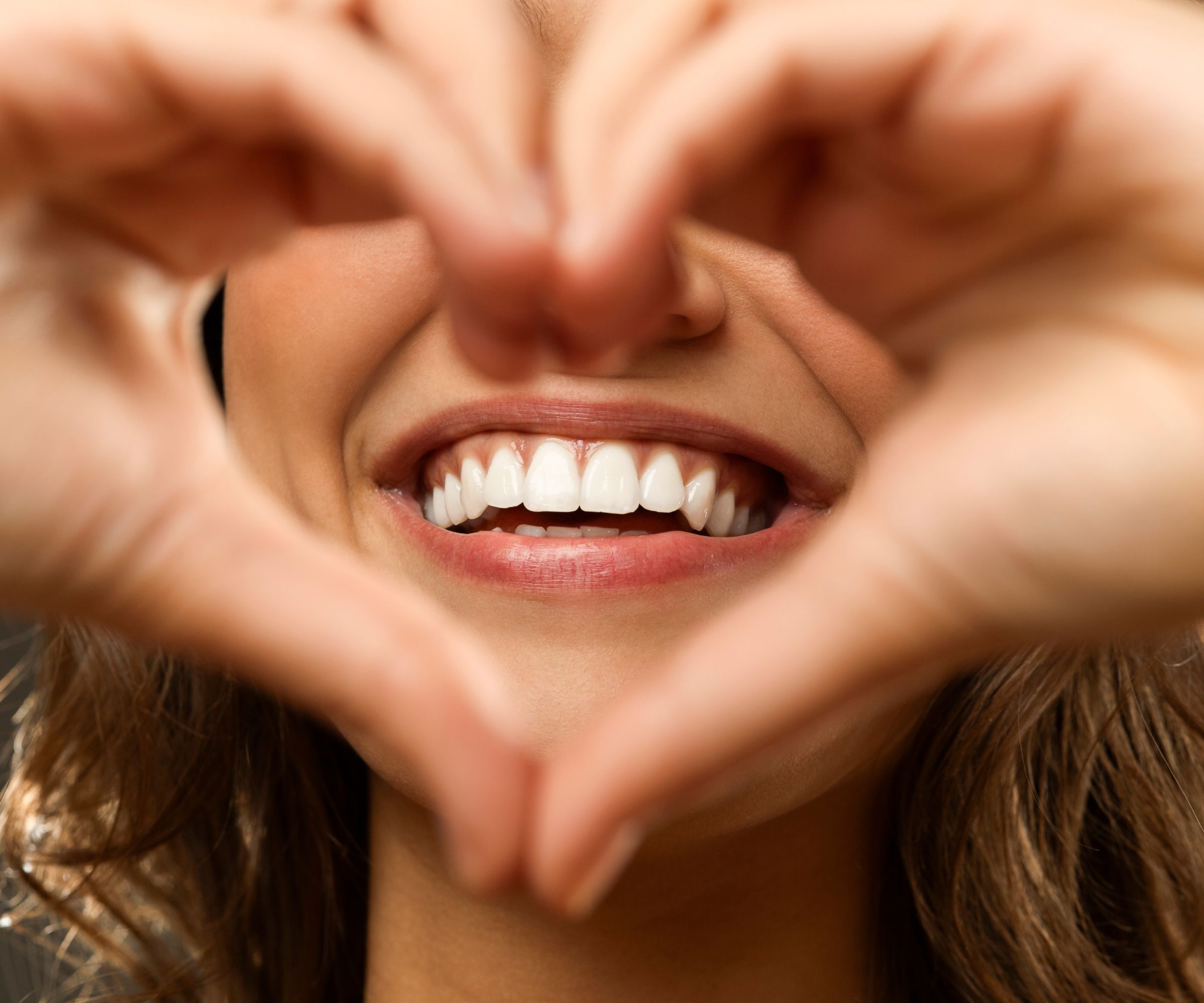 Close-up of smiling mouth framed by hands