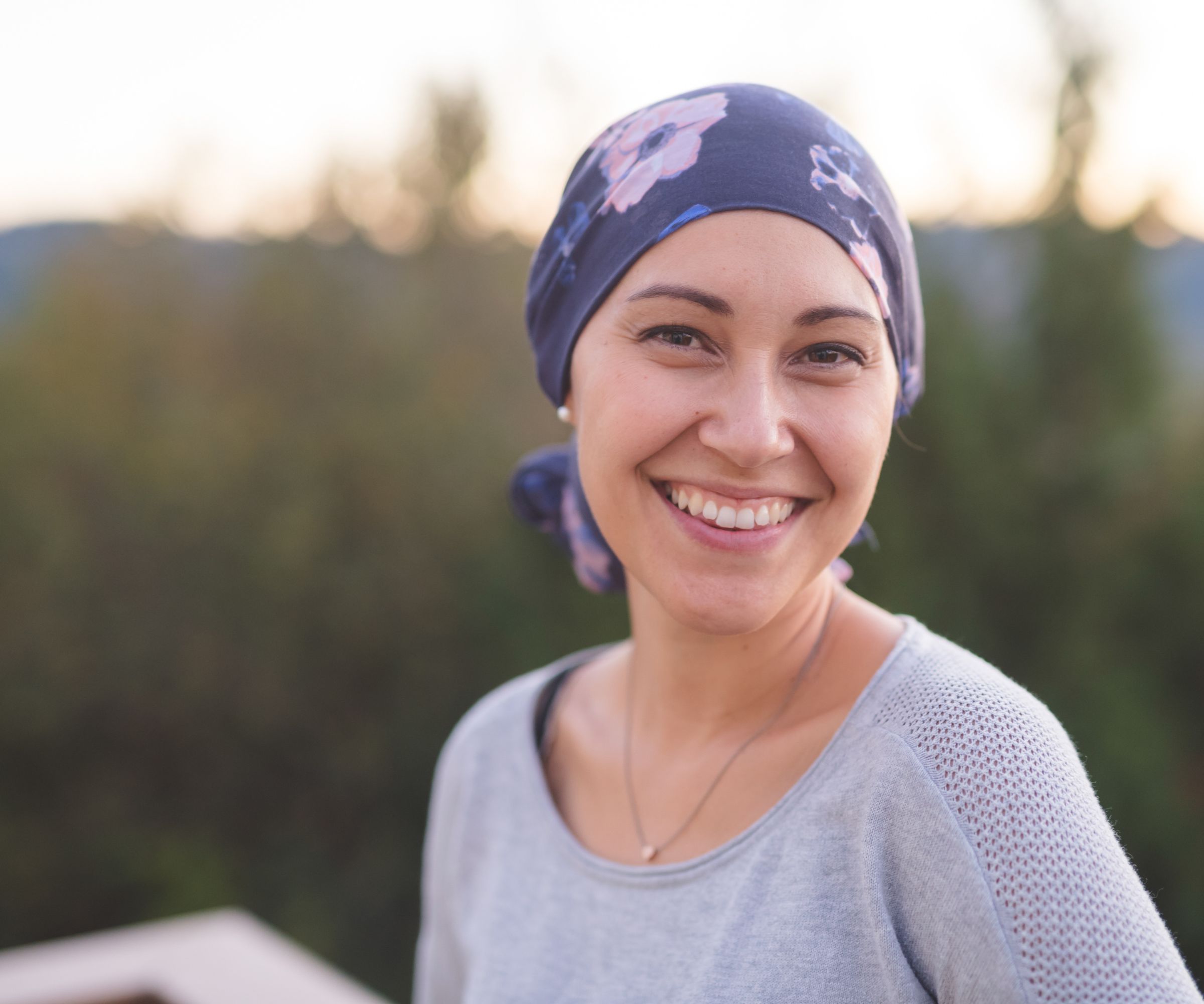 Smiling woman wearing floral headscarf outdoors at sunset