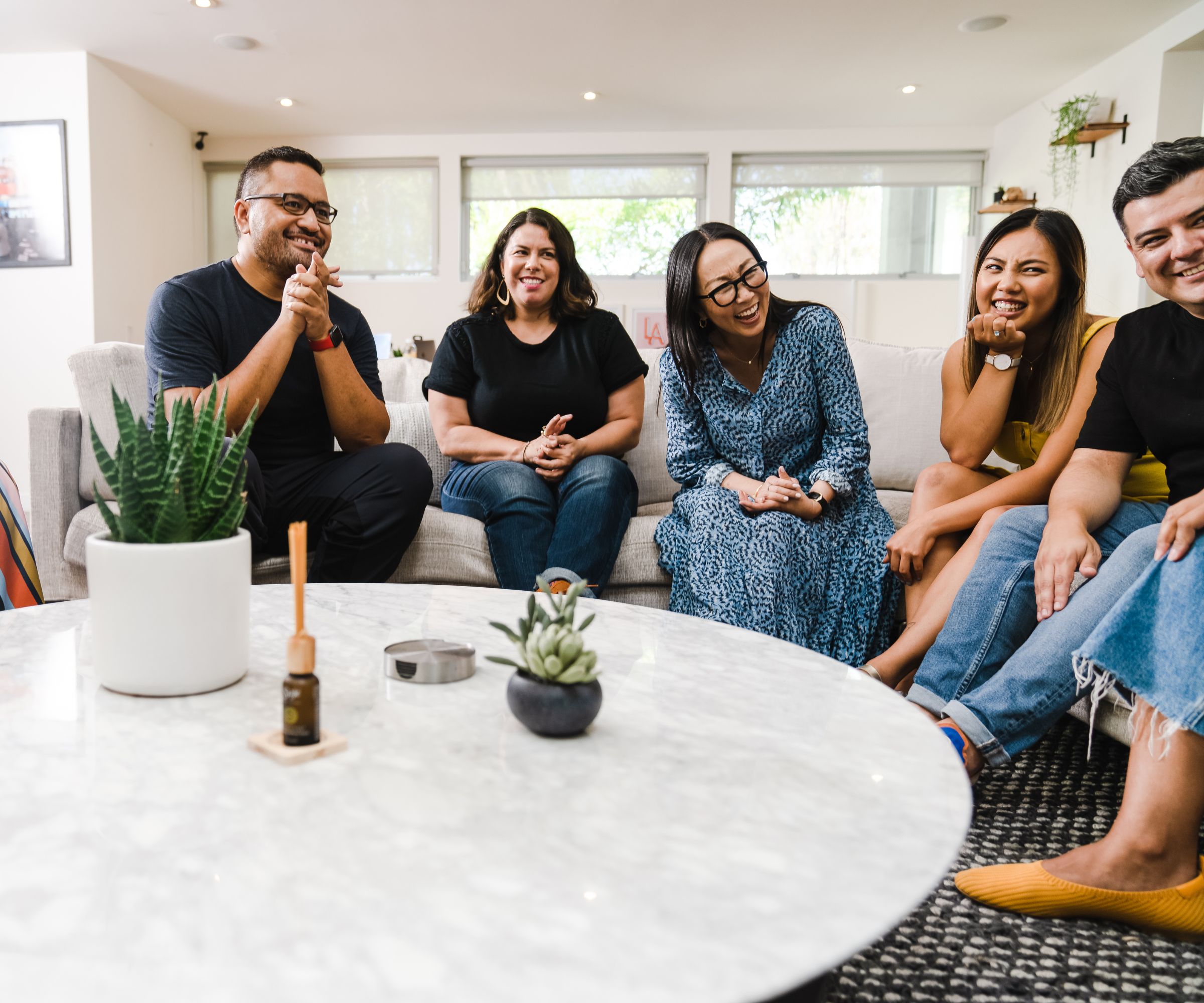Five friends laughing together on living room couch