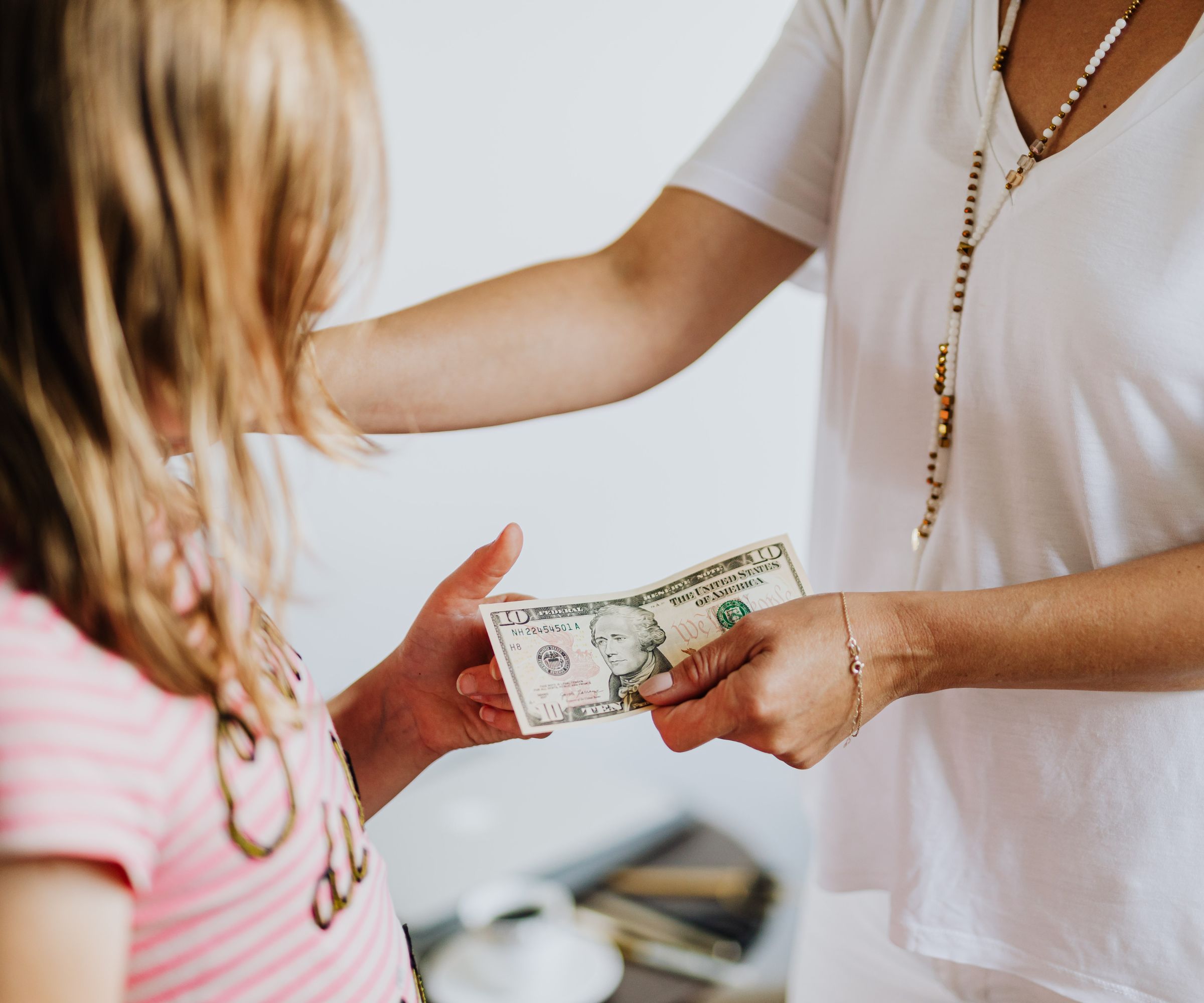 Adult giving ten dollar bill to child