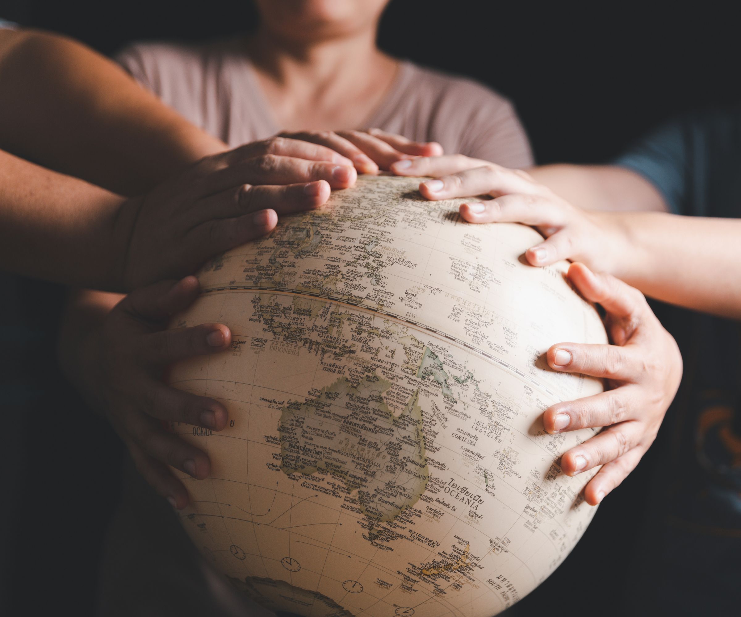 Hands joined together on a world globe
