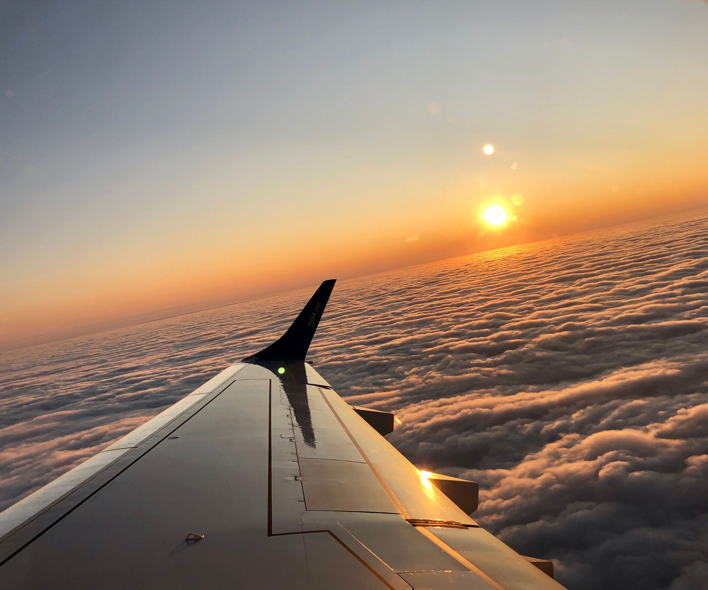 Airplane wing above clouds at sunset