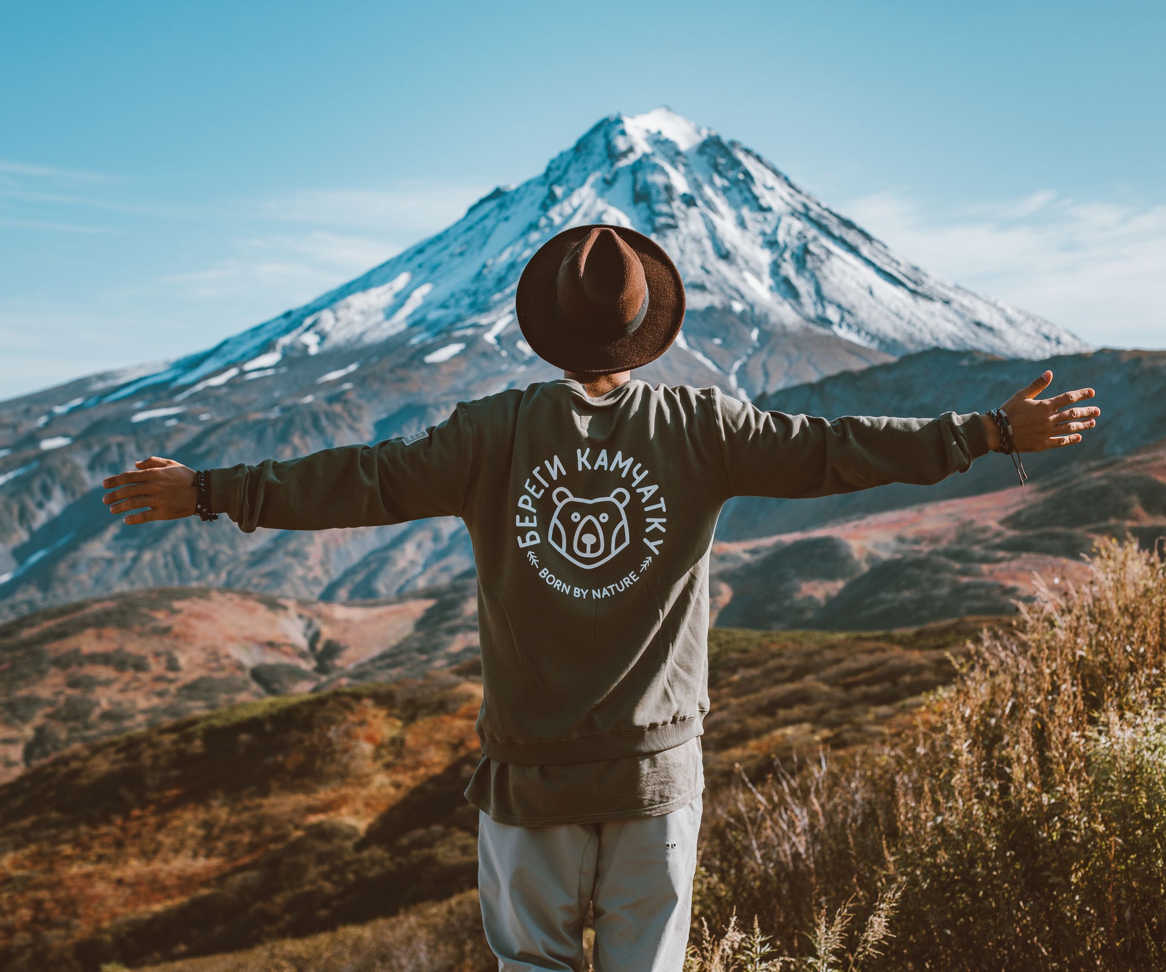 Person with outstretched arms facing snow-capped mountain