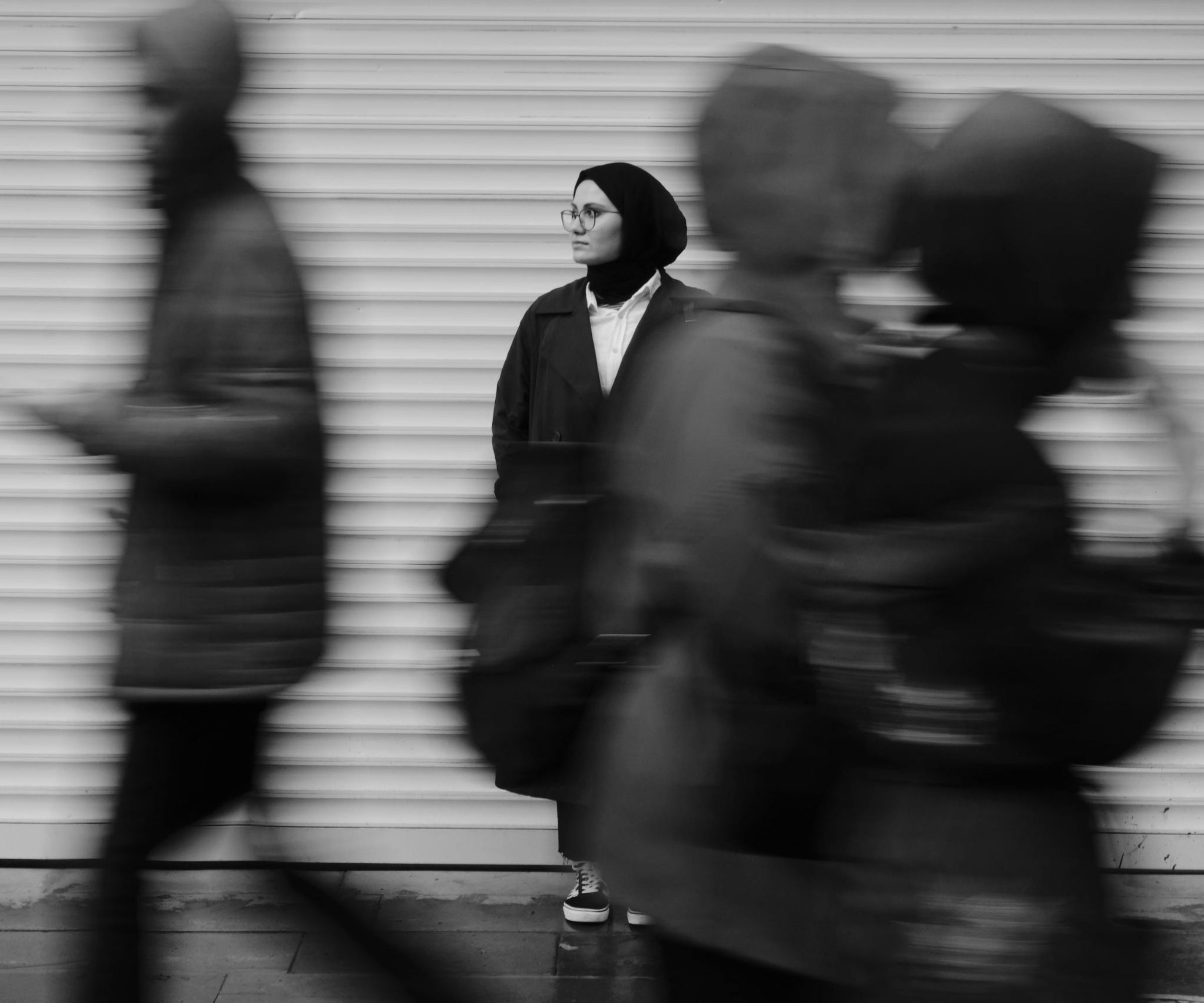Woman in headscarf standing amid blurred pedestrians