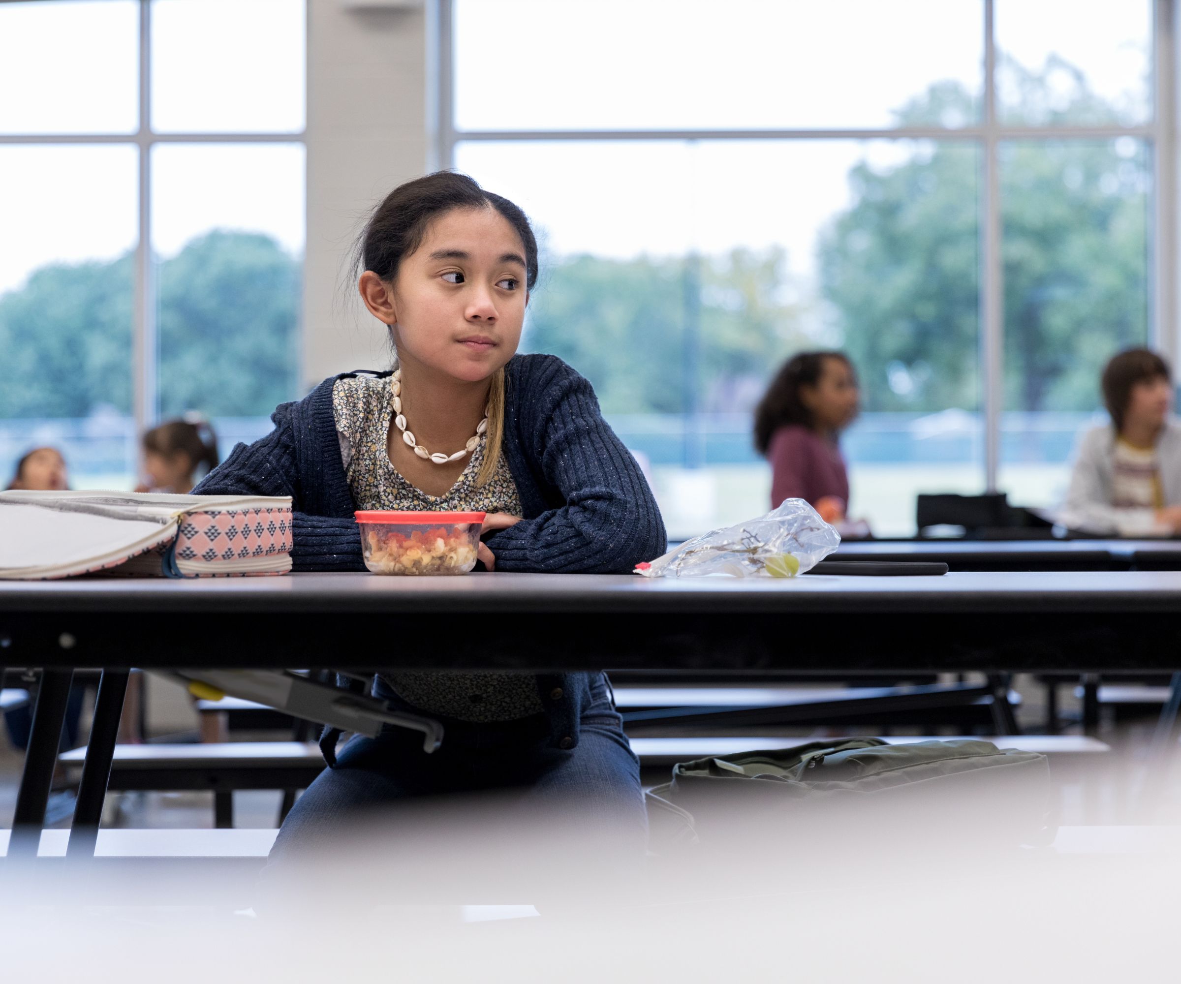 Student sitting alone at cafeteria table with lunch