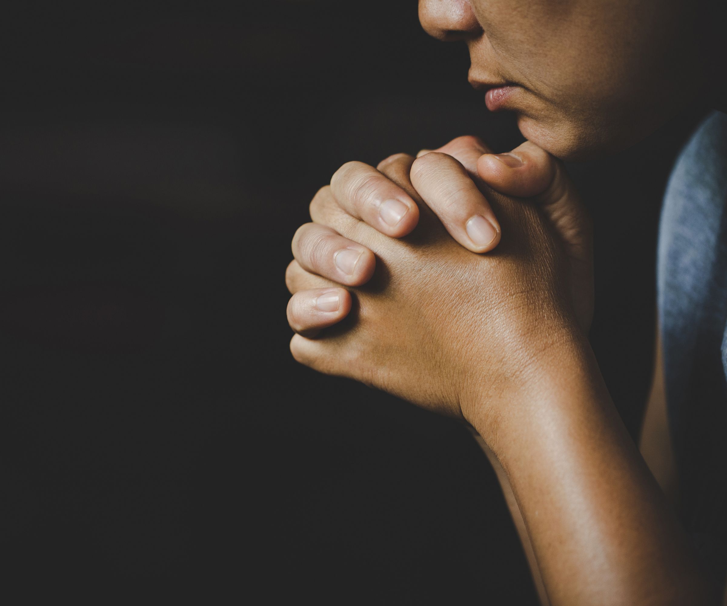 Person with clasped hands in prayer or reflection